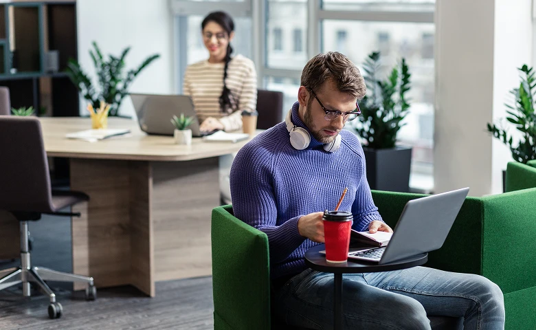 Man working on a laptop in a green armchair