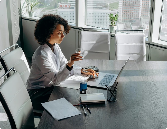 Woman working on a laptop beside a window