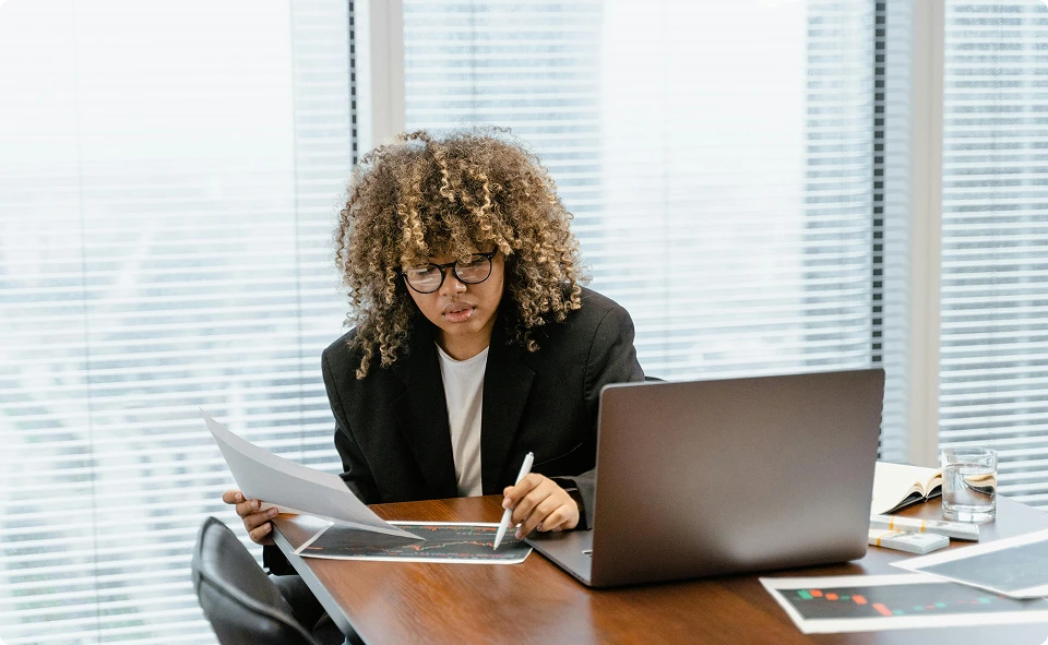 Woman reviewing papers next to a laptop