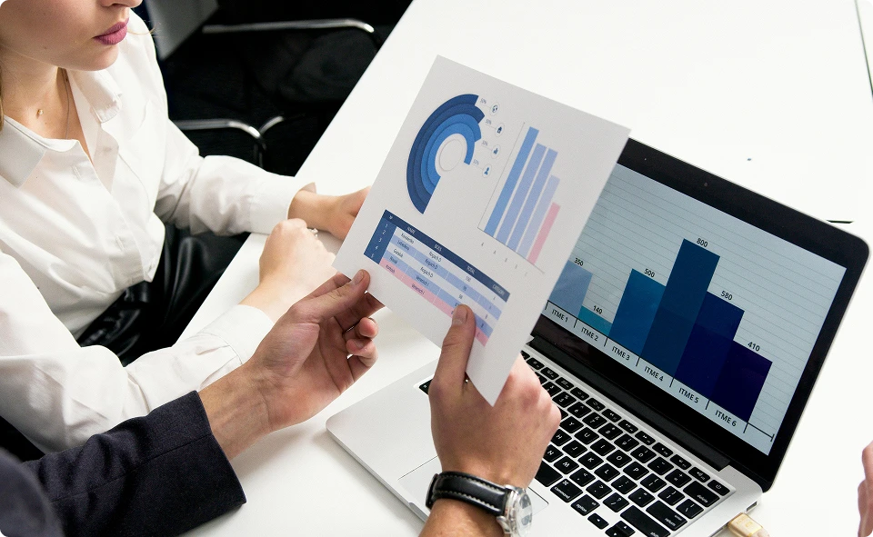Hands holding a printed chart beside a laptop